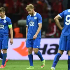 Smutni piłkarze Dnipro Dniepropietrowsk w niebieskich strojach schodzą z boiska po przegranym meczu.