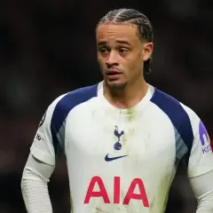 Piłkarz Tottenhamu w białej koszulce z granatowymi detalami, z charakterystyczną fryzurą.