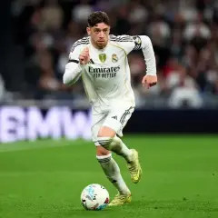 Piłkarz Realu Madryt, Valverde, w akcji. Jego numer na koszulce jest dobrze widoczny, gdy biegnie z piłką po zielonej murawie stadionu.