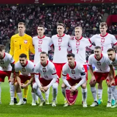 Piłkarze reprezentacji Polski w białych strojach pozują na murawie stadionu.