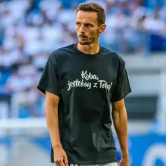 Rafał Wolski, komentator, na boisku w koszulce "Kuba, jesteśmy z Tobą!".