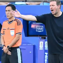 Trener Niemiec gestykuluje, dyskutując z arbitrem podczas meczu.