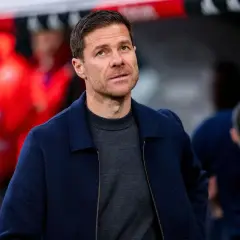 Xabi Alonso, potencjalny trener Chelsea, w granatowej kurtce i szarym swetrze, z uwagą obserwuje boisko.