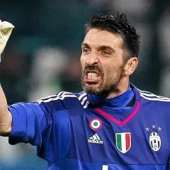 Buffon bramkarz w niebieskiej koszulce Juventusu z podniesioną rękawicą, zacięty wyraz twarzy.