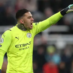 Bramkarz Manchester City w żółtej koszulce, z podniesioną ręką, gotowy do akcji. Skład Manchester City.