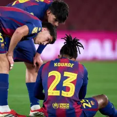 Piłkarze FC Barcelona zmartwieni po kontuzji kolegi. Koundé siedzi na murawie, koledzy pochylają się nad nim.