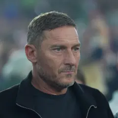 Francesco Totti, legenda piłkarzy z Rzymu, w czarnej kurtce, z uwagą obserwuje wydarzenia.