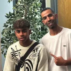 Mounir Nasraoui z młodym chłopcem pozują do zdjęcia obok sztucznej rośliny.
