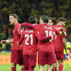 Piłkarze w czerwonych koszulkach świętują, czy polska jedzie na mundial? Zwycięstwo na boisku.