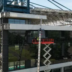 Prace przy stadionie Wisły po remoncie. Dwóch robotników na podnośniku montuje szklaną fasadę.