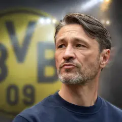 Twarz trenera Borussii Dortmund, z charakterystycznym logo klubu w tle.