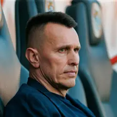 Skupiony trener Zagłębia Lubin siedzi na ławce rezerwowych, analizując grę.