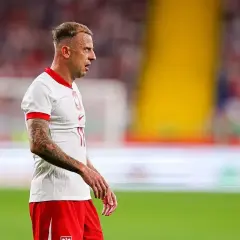 Piłkarz Kamil Grosicki w białej koszulce i czerwonych spodenkach, z tatuażami na ramieniu. Jego majątek to wynik ciężkiej pracy na boisku.