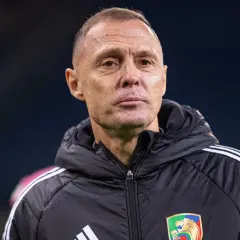 Trener Stali Mielec w czarnej kurtce z białymi pasami na ramionach, z emblematem klubu na piersi.