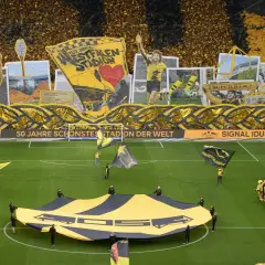 Wspaniała oprawa kibiców na stadionie Dortmund. Żółto-czarne barwy dominują, a fani tworzą gigantyczną flagę i transparenty.