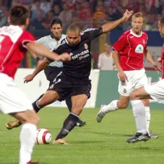 Piłkarz w czarnej koszulce Realu Madryt, gdzie grał Ronaldo, strzela gola.