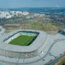 Nowoczesny stadion w Sosnowcu, ArcelorMittal Park, z zieloną murawą i trybunami. Jego pojemność pozwala na przyjęcie wielu kibiców.