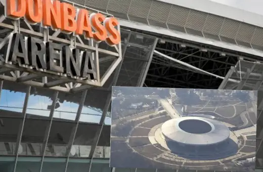 Zbliżenie na napis "DONBAS ARENA" nad nowoczesnym stadionem widzianym z lotu ptaka.