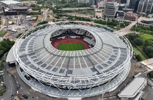 Widok z lotu ptaka na londyński stadion z zieloną murawą i bieżnią. Dach pokryty panelami słonecznymi.