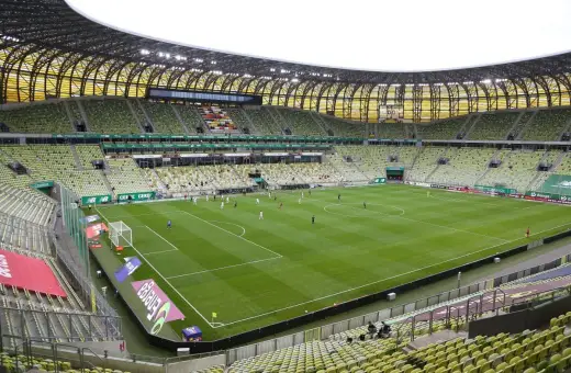 Stadion Lechii Gdańsk, z zielonymi trybunami i murawą, gotowy na mecz. Jego pojemność robi wrażenie.