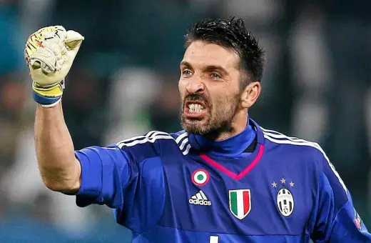 Buffon bramkarz w niebieskiej koszulce Juventusu z podniesioną rękawicą, zacięty wyraz twarzy.