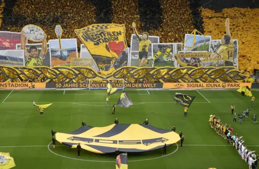 Wspaniała oprawa kibiców na stadionie Dortmund. Żółto-czarne barwy dominują, a fani tworzą gigantyczną flagę i transparenty.