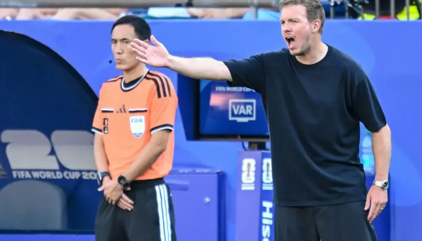 Trener Niemiec gestykuluje, dyskutując z arbitrem podczas meczu.