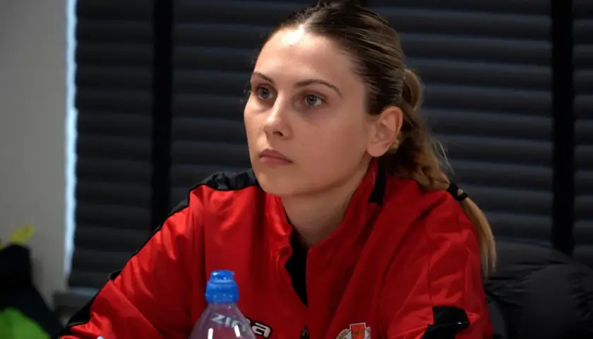 Młoda kobieta w czerwonej bluzie, przyszły trener UEFA A, słucha uważnie.