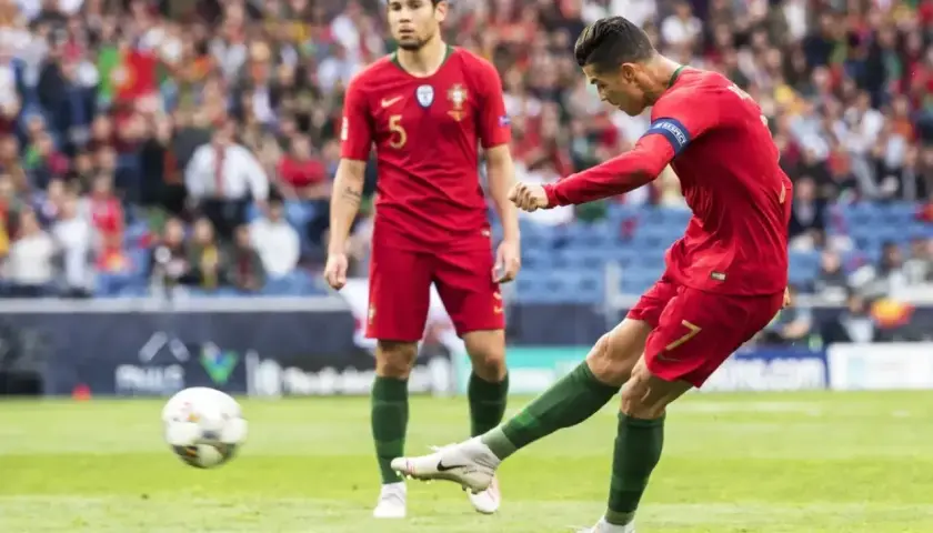 Piłkarz Portugalii Cristiano Ronaldo strzela gola, podczas gdy jego kolega z drużyny obserwuje. Mecz Portugalia - Szwajcaria.