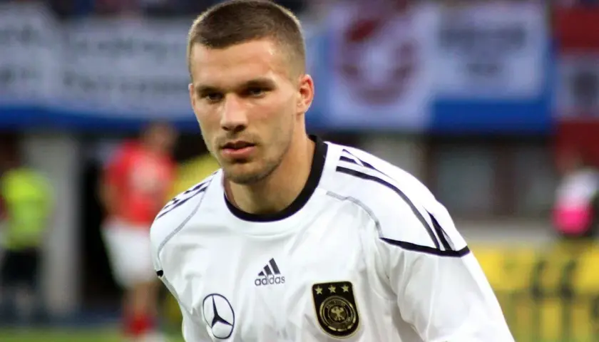 Piłkarz w białej koszulce reprezentacji Niemiec, z orłem i trzema gwiazdkami. To młody Podolski, gotowy do gry.