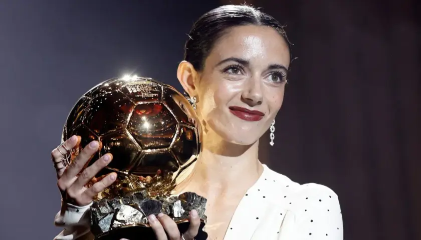 Piłkarka z dumą trzyma złotą piłkę kobiet, symbol najwyższego uznania w świecie futbolu.