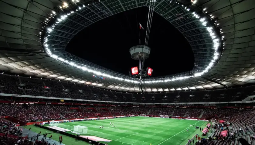 Widok na murawę i trybuny największego stadionu w Polsce. Rozświetlony dach i jupitery tworzą niesamowitą atmosferę.