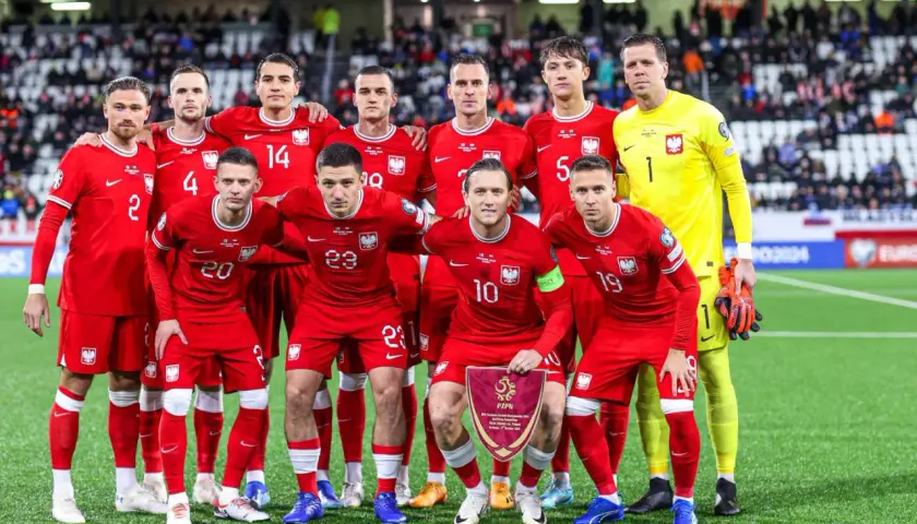 Piłkarze reprezentacji Polski w czerwonych strojach, gotowi do gry. Drużyna, która jak polska wyspy owcze, walczy o zwycięstwo.