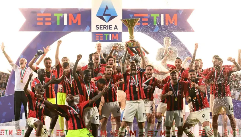 Piłkarze świętują zdobycie scudetto, unosząc puchar Serie A wśród konfetti i fajerwerków.