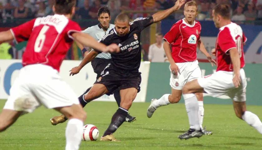 Piłkarz w czarnej koszulce Realu Madryt, gdzie grał Ronaldo, strzela gola.