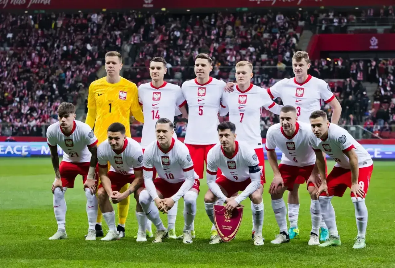Piłkarze reprezentacji Polski w białych strojach pozują na murawie stadionu.
