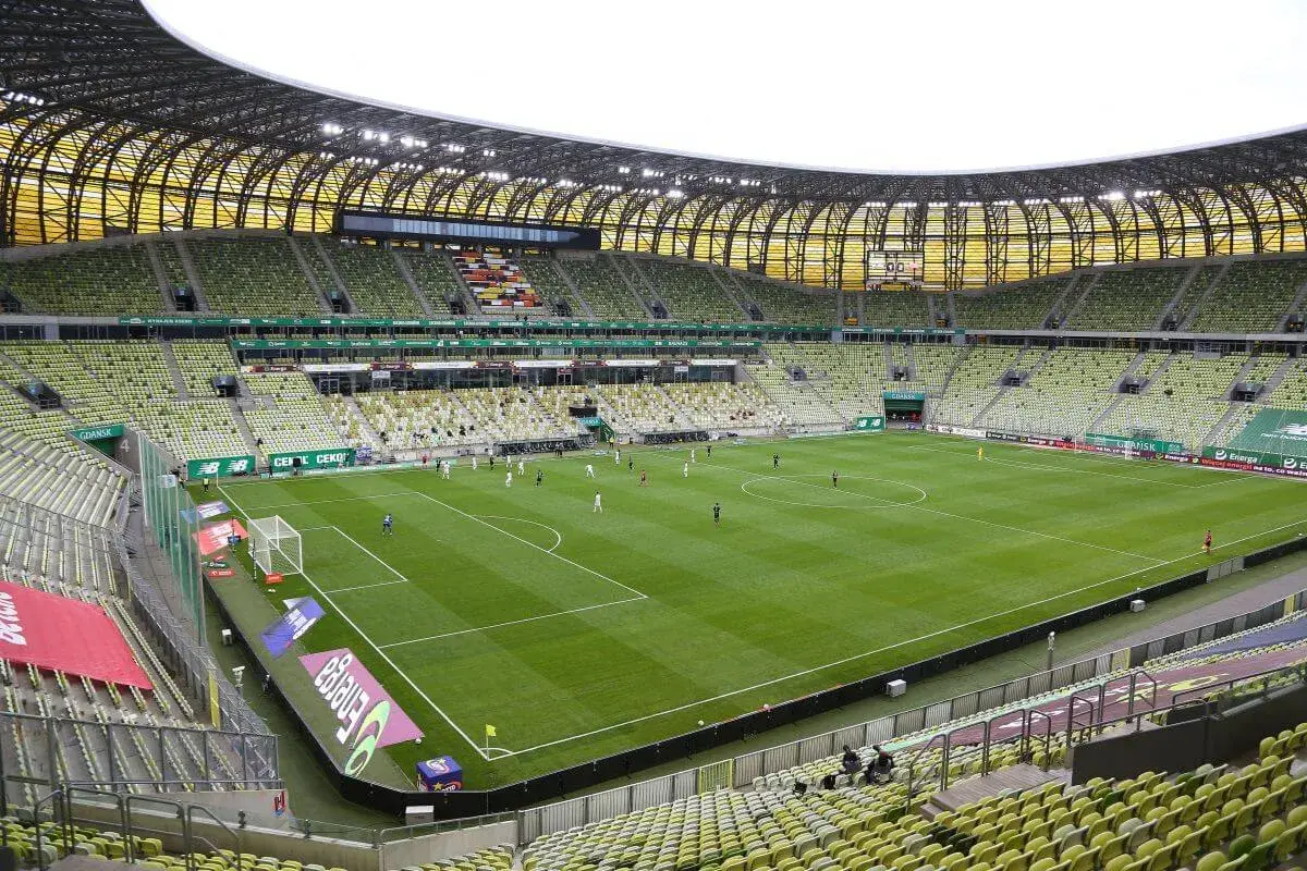 Stadion Lechii Gdańsk, z zielonymi trybunami i murawą, gotowy na mecz. Jego pojemność robi wrażenie.