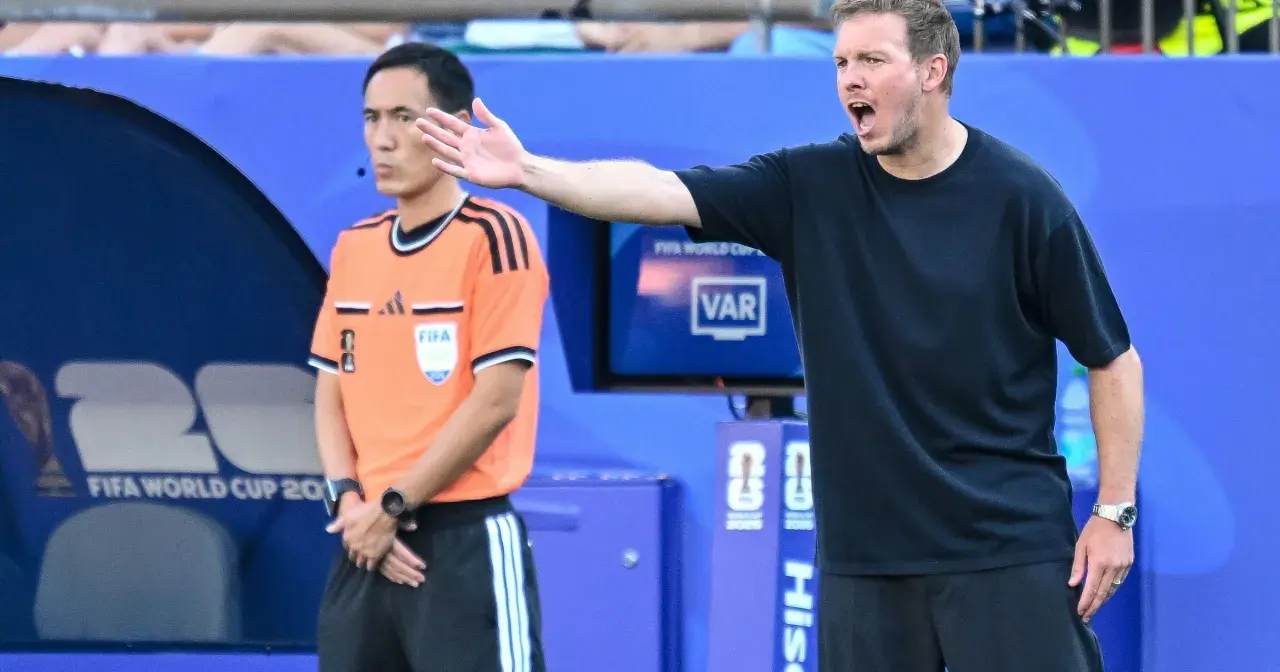 Trener Niemiec gestykuluje, dyskutując z arbitrem podczas meczu.