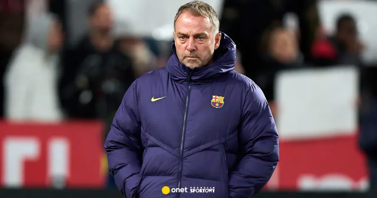 Zamyślony trener Barcelony w granatowej kurtce z herbem klubu.
