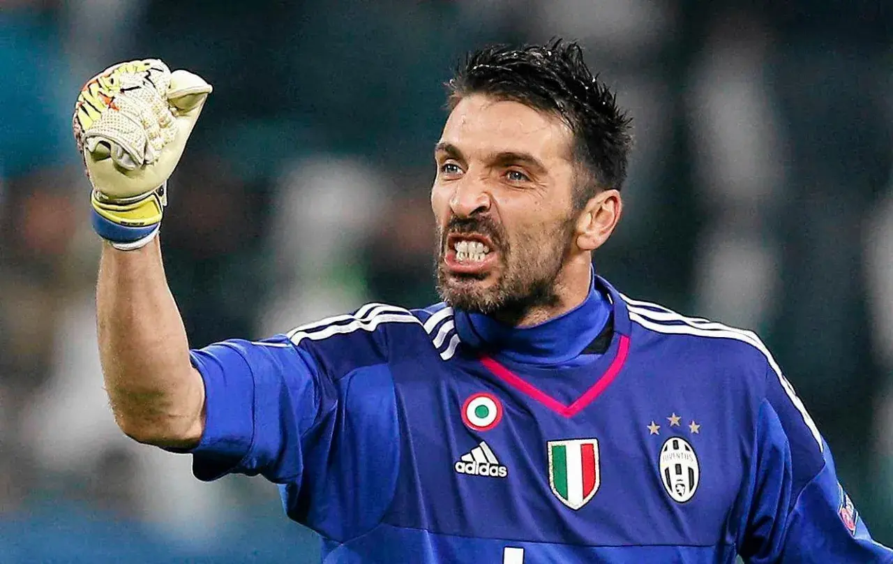 Buffon bramkarz w niebieskiej koszulce Juventusu z podniesioną rękawicą, zacięty wyraz twarzy.