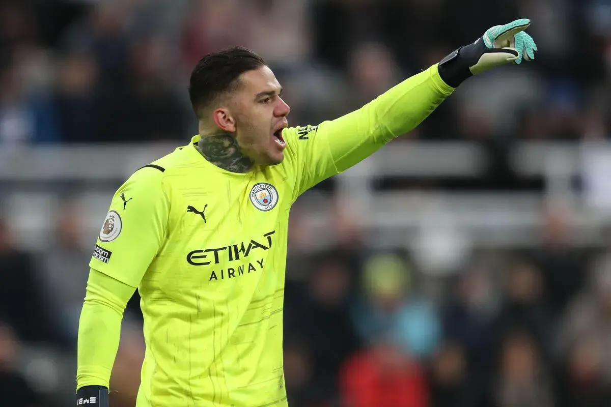 Bramkarz Manchester City w żółtej koszulce, z podniesioną ręką, gotowy do akcji. Skład Manchester City.
