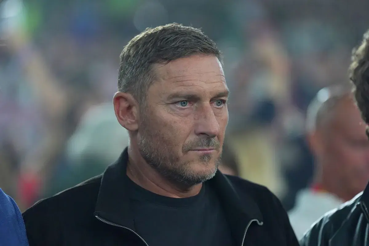 Francesco Totti, legenda piłkarzy z Rzymu, w czarnej kurtce, z uwagą obserwuje wydarzenia.