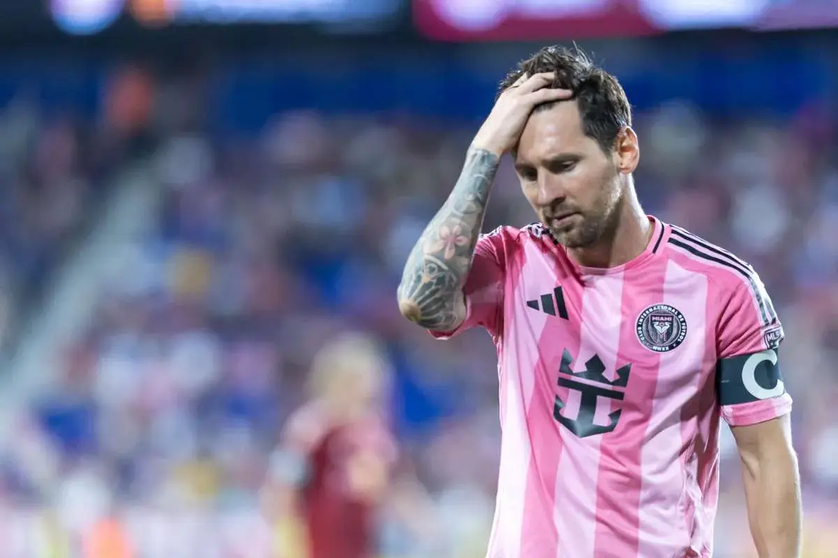 Lionel Messi w różowej koszulce Interu Miami, z ręką na głowie, wyraża zmartwienie. Czyżby to była **messi kontuzja**?