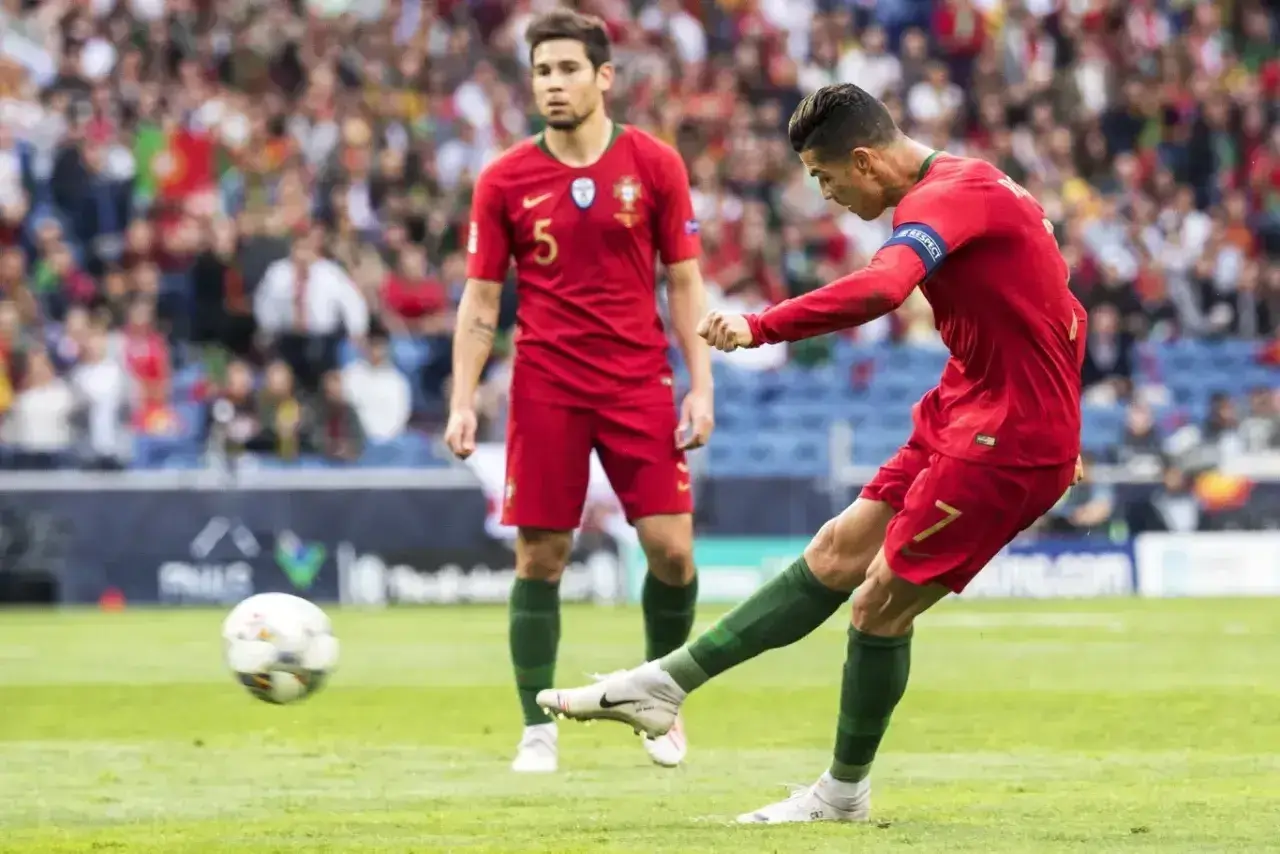 Piłkarz Portugalii Cristiano Ronaldo strzela gola, podczas gdy jego kolega z drużyny obserwuje. Mecz Portugalia - Szwajcaria.