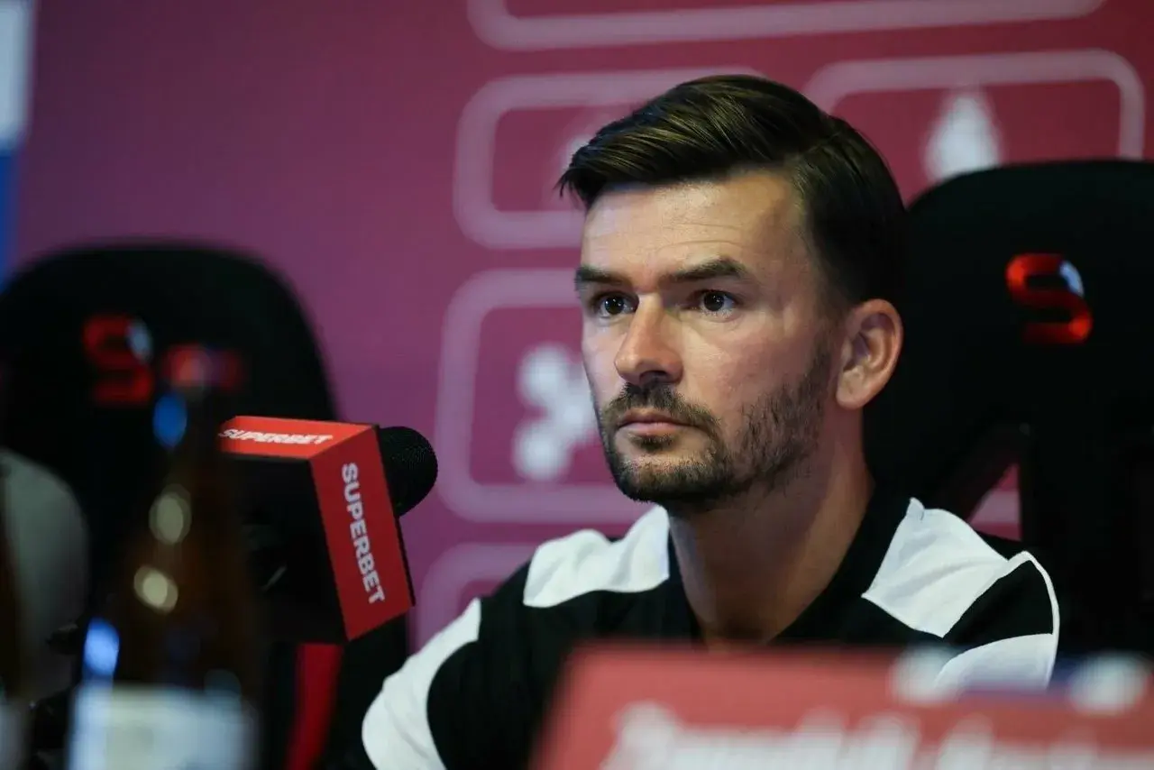 Trener Górnika Zabrze, w czarno-białej koszulce, siedzi przy mikrofonie Superbet.