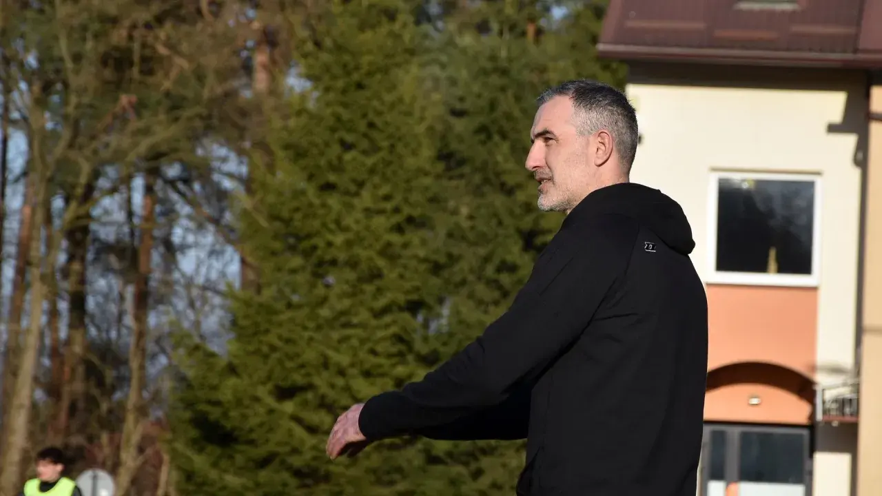 Szeliga trener w czarnej bluzie, z uwagą obserwuje boisko.