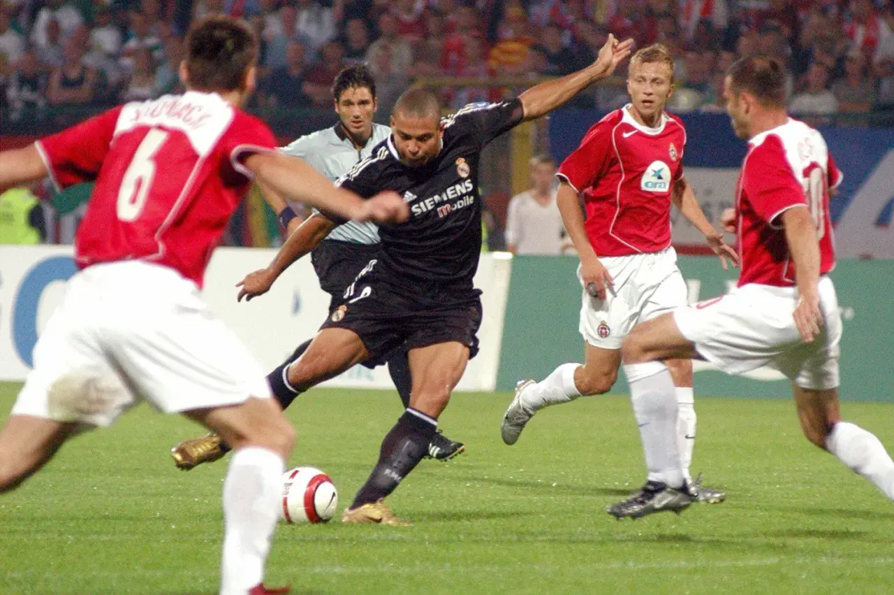 Piłkarz w czarnej koszulce Realu Madryt, gdzie grał Ronaldo, strzela gola.