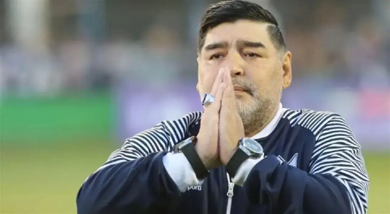 Diego Maradona na co zmarł? Legenda futbolu z dłońmi złożonymi w geście modlitwy, w charakterystycznej bluzie.