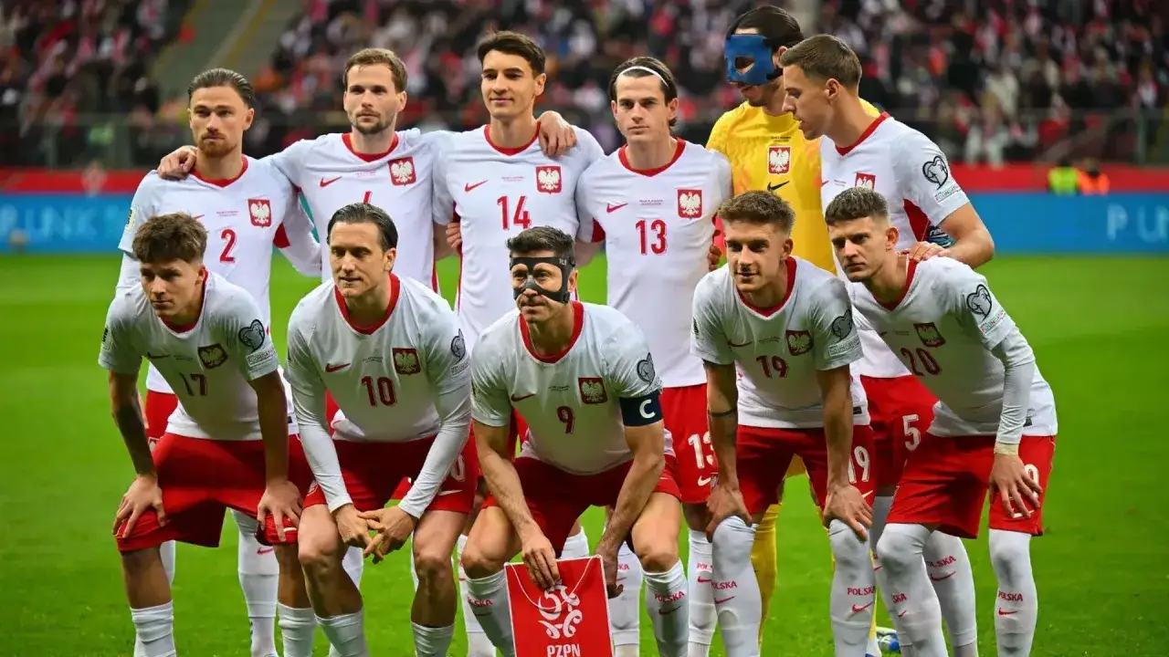 Piłkarze polscy w białych strojach z orzełkiem na piersi, gotowi do gry. Robert Lewandowski w masce na twarzy.