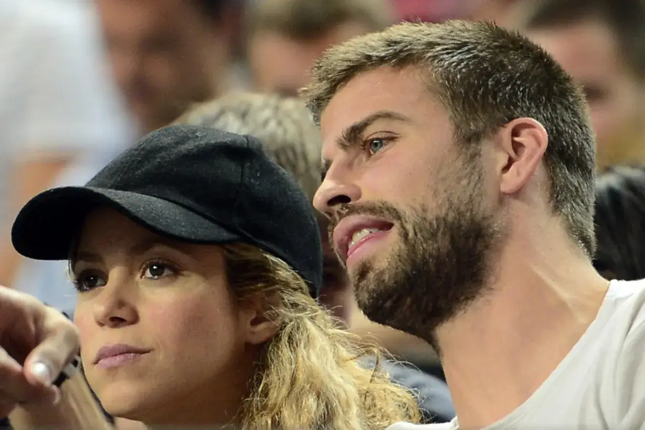 Shakira w czapce i Gerard Piqué, para znana z mediów, oglądają wydarzenie sportowe.